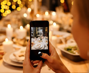 A lady photographing a richly spread table with a smartphone